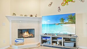 A living room with a fireplace, a flat-screen TV, and a wooden entertainment unit. - SaltyLux16 Heated Saltwater Pool/Near Beach/Island (Clearwater)
