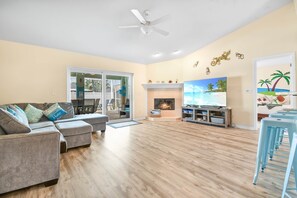 A living room with a sofa, a TV, a fireplace, and a ceiling fan. - SaltyLux16 Heated Saltwater Pool/Near Beach/Island (Clearwater)