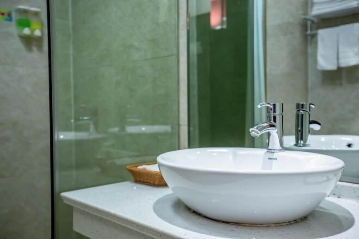 A bathroom with a white sink, two faucets, and a glass shower enclosure.