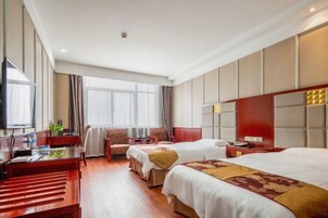 A hotel room with two beds, a desk, a chair, and a television.
