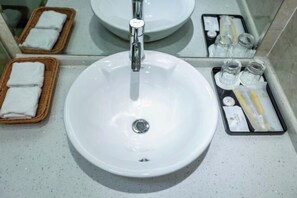 A bathroom with a white sink, a mirror, and a tray with toiletries. - Haotai Hotel (Ruian Jianye) (Lu'an)