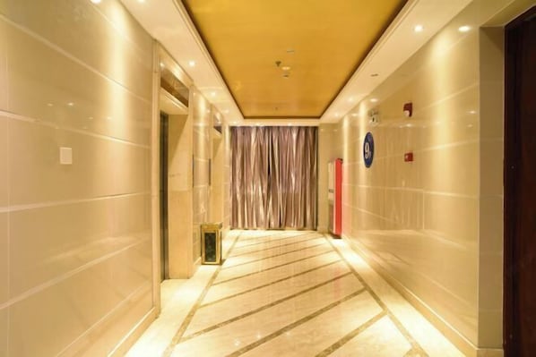 A hallway with a marble floor, a golden ceiling, and a red emergency exit sign. - Haotai Hotel (Ruian Jianye) (Lu'an)