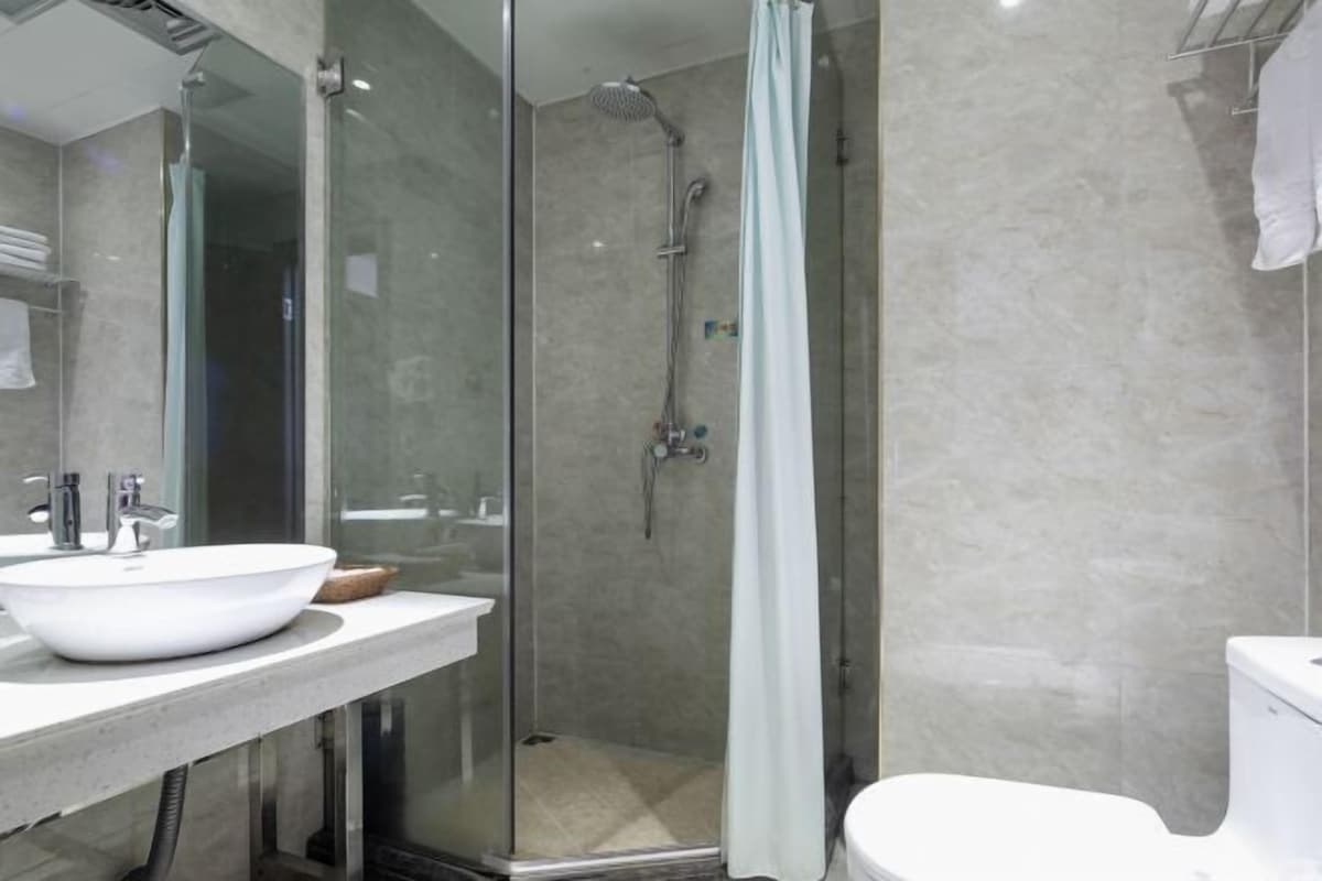 A modern bathroom with a glass-enclosed shower, a white sink, and a toilet.