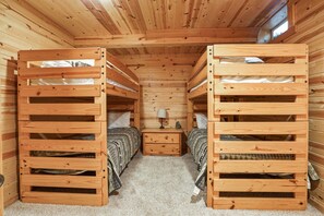 A wooden cabin with bunk beds, a small bedside table with a lamp, and a window. - Cabin Fever | Hocking, Hot Tub, Pets, Firepit (Logan)