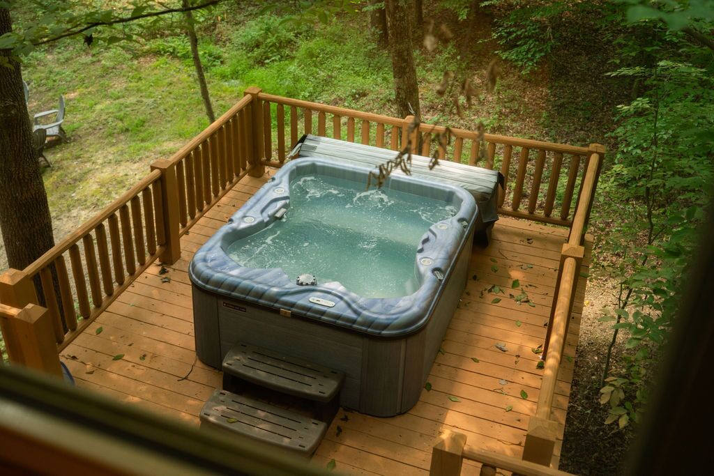 Ein Whirlpool auf einer Holzterrasse, umgeben von Bäumen.