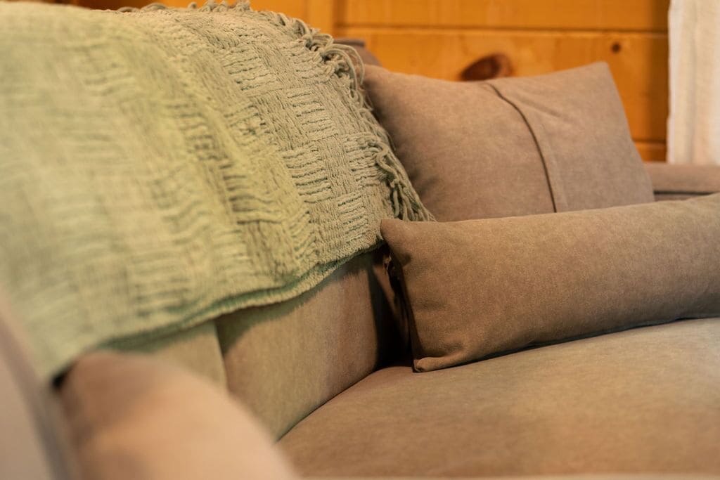 Un gros plan d’un canapé avec un plaid texturé et un coussin.