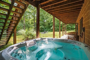 A hot tub under a wooden pergola with a view of a lush garden. - Sieri Glen Cabin | Hocking Hills, Sleeps 14 (Logan)
