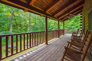 A wooden deck with a railing overlooking a forested area.