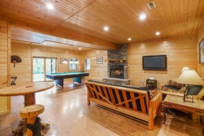 Un intérieur en bois avec une table de billard, un canapé et une cheminée.