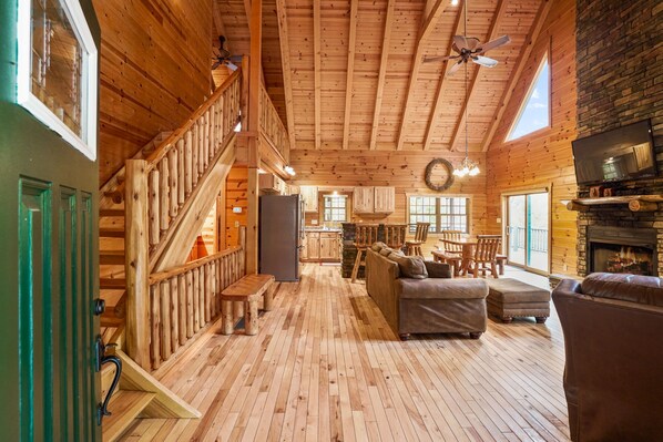 A spacious wooden interior with a staircase, seating area, and a fireplace.