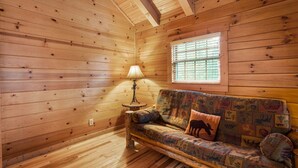 A wooden interior with a sofa, a lamp, and a window with blinds. - Sieri Glen Cabin | Hocking Hills, Sleeps 14 (Logan)