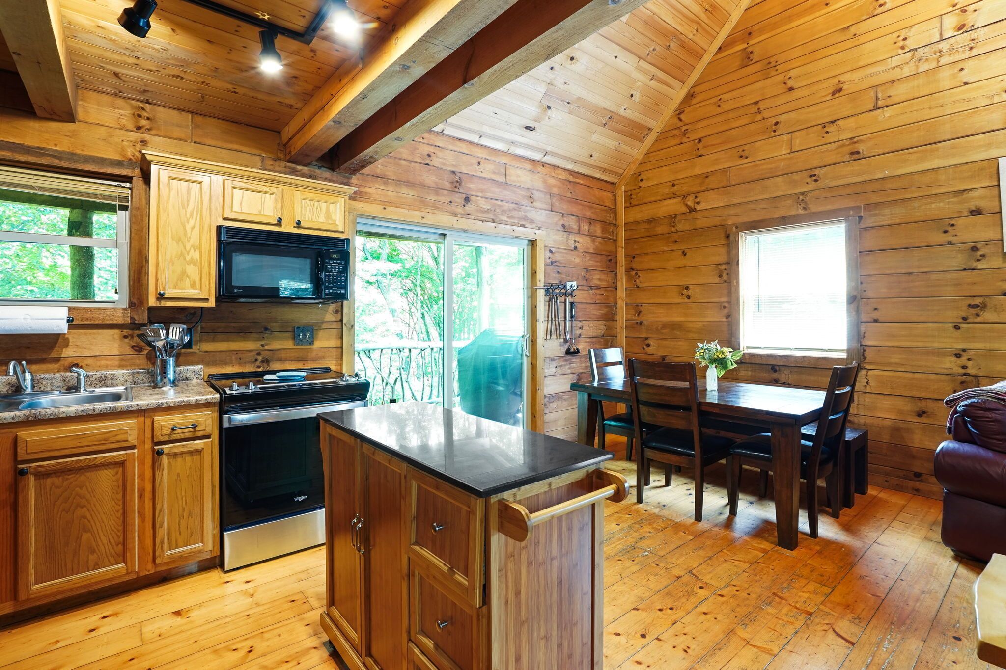 A wooden cabin interior with a kitchen, dining area, and a fireplace.