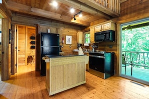 A wooden cabin kitchen with a central island, a refrigerator, a microwave, and a sink.