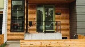 A modern two-story house with a large glass window, a wooden front porch, and a small garden area. - The Cowboy Inn - Luxury Bozeman (Bozeman)