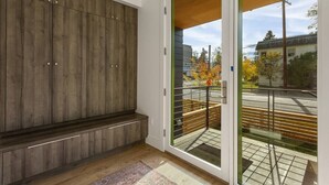 A modern interior with a wooden panel wall, a glass door leading to an outdoor balcony, and a patterned rug on the floor. - The Cowboy Inn - Luxury Bozeman (Bozeman)