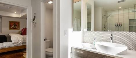 A modern bathroom with a large mirror, a white sink, and a shower.