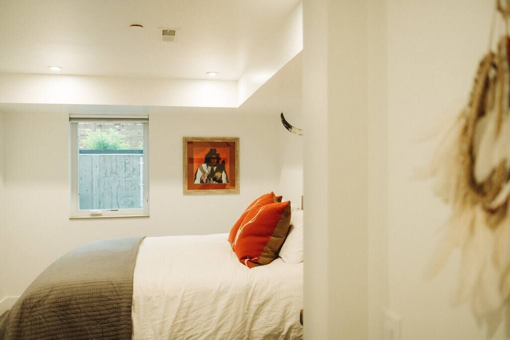 Un dormitorio con cama, ventana y un cuadro en la pared.