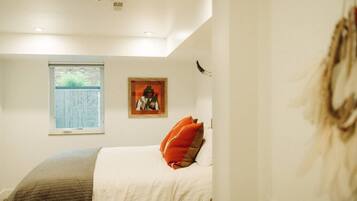 Un dormitorio con cama, ventana y un cuadro en la pared.