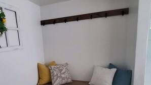 A corner room with a built-in bench, a small black rug, and a window with a plant. - The White House Cottage (Inkom)