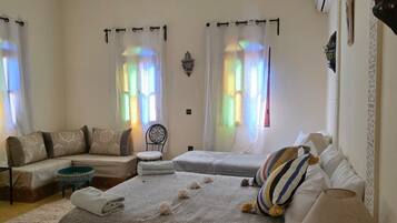 A bedroom with a large bed, two smaller beds, a sofa, a chair, and a small table.