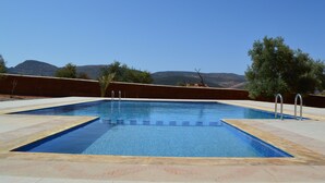 En rektangulär swimmingpool med klart blått vatten, omgiven av en kakelbeklädd poolterrass.