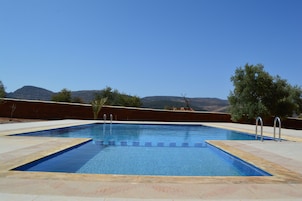 A rectangular swimming pool with clear blue water, surrounded by a tiled deck.