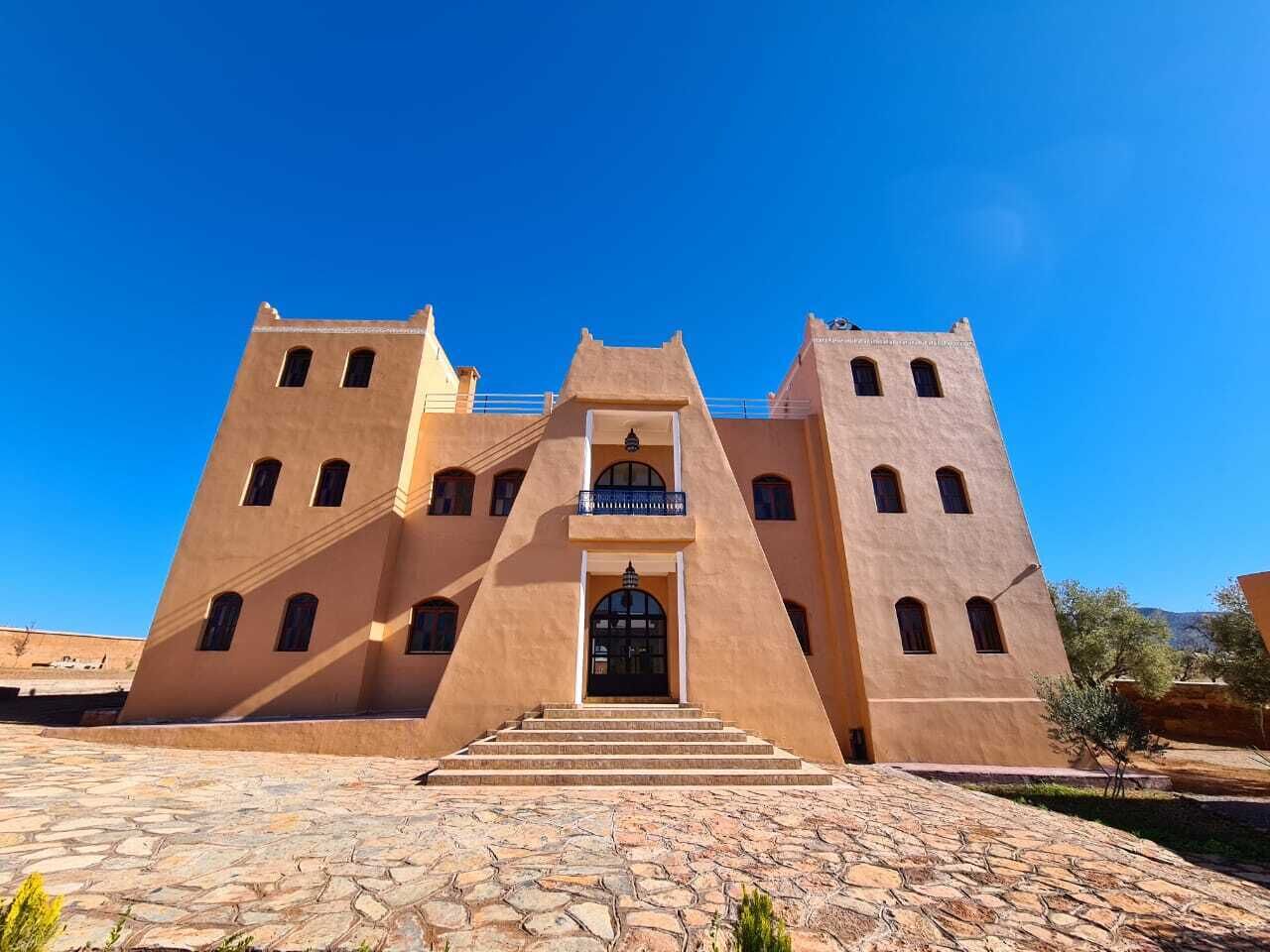 A large, symmetrical building with a central entrance, multiple windows, and a stone-paved courtyard.