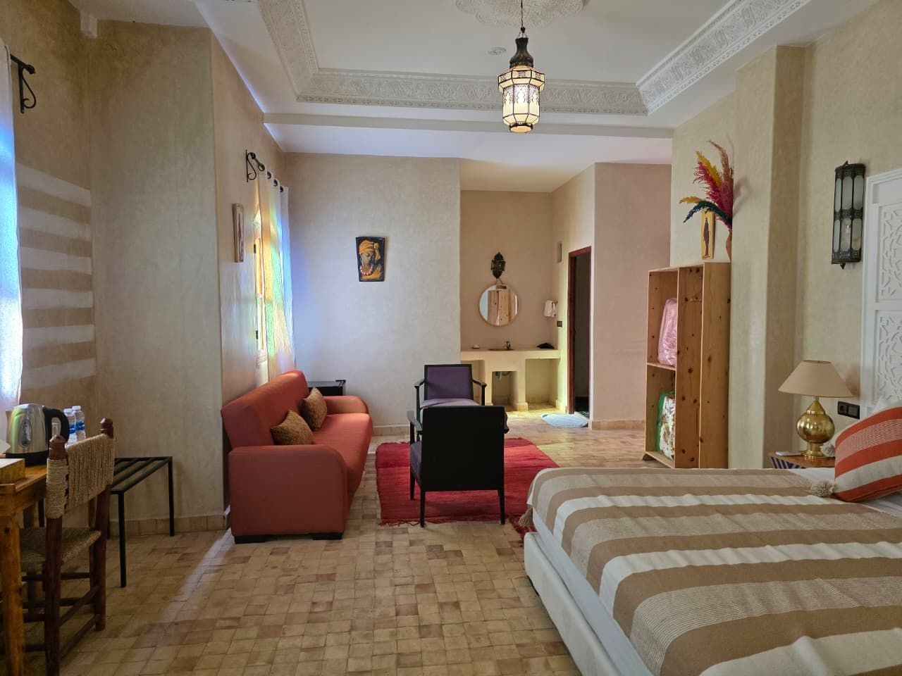 A hotel room with a bed, a sofa, a desk, and a chair.