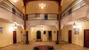 A spacious interior with a high ceiling, ornate railings, and a central staircase. - KASBAH NTIFA (Ait Taguella)