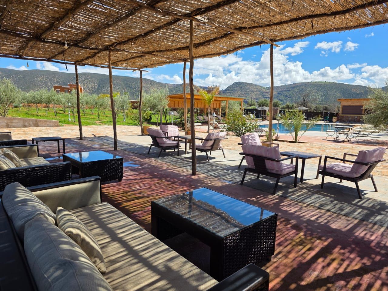 Un espace extérieur aménagé avec des tables et des chaises, une piscine et un paysage montagneux en toile de fond.