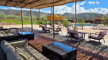 Un espace extérieur aménagé avec des tables et des chaises, une piscine et un paysage montagneux en toile de fond.