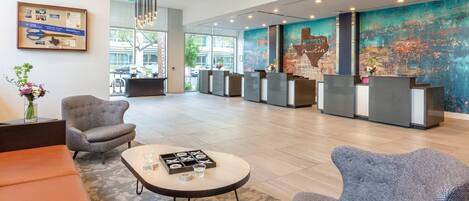 A modern lobby with a reception desk, seating area, and a large wall mural.