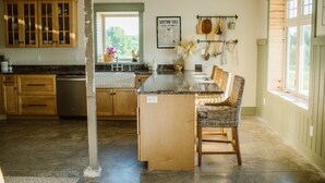 Una cocina con armarios de madera, encimera de granito y una isla central con una silla de mimbre.