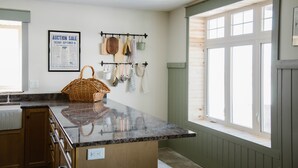 Cocina con encimera de granito, armarios de madera, colgador para ollas y ventana con vistas.