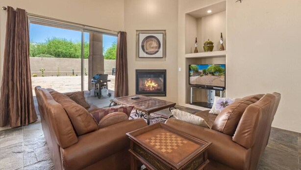 A living room with leather sofas, a fireplace, a television, and a chess table. - Troon/Gated/Pool/Firepit/Sleep 6 (Scottsdale)