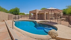 A swimming pool with a stone border, a covered seating area with an umbrella, and a fenced patio. - Troon/Gated/Pool/Firepit/Sleep 6 (Scottsdale)