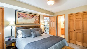 A bedroom with a large bed, a nightstand, a lamp, a wooden bench, and a door leading to another room. - Waterfront Johnson Lake Getaway w/ Fire Pit! (Johnson Lake)