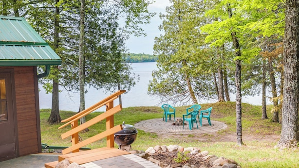 Een vakantiehuis aan het meer met een houten terras, een barbecue en buitenmeubels.
