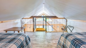 Een tentkamer met twee bedden, een tafel, een ventilator en een trap naar een hoger niveau.
