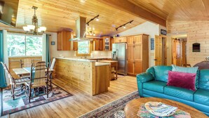 A spacious living area with a wooden ceiling, a central island with seating, and a sofa with a cushion. - Waterfront Eagle River Home w/ Dock + Fire Pit! (Eagle River)