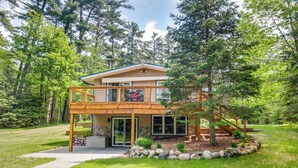 A two-story house with a balcony, a stone fireplace, and a stone retaining wall. - Waterfront Eagle River Home w/ Dock + Fire Pit! (Eagle River)