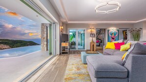Una sala de estar moderna con un ventanal que ofrece una vista panorámica, un sofá gris con cojines de colores y una alfombra estampada.