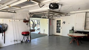 A garage with a concrete floor, a red barbecue grill, fishing rods, and a table. - Salty River Lodge Arroyo City, TX (Cameron County)