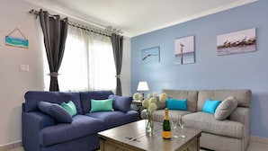A living room with two sofas, a coffee table with a bottle and glasses, and a lamp.