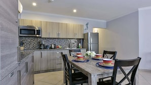 A modern kitchen with a built-in microwave, stainless steel refrigerator, and a tiled backsplash.
