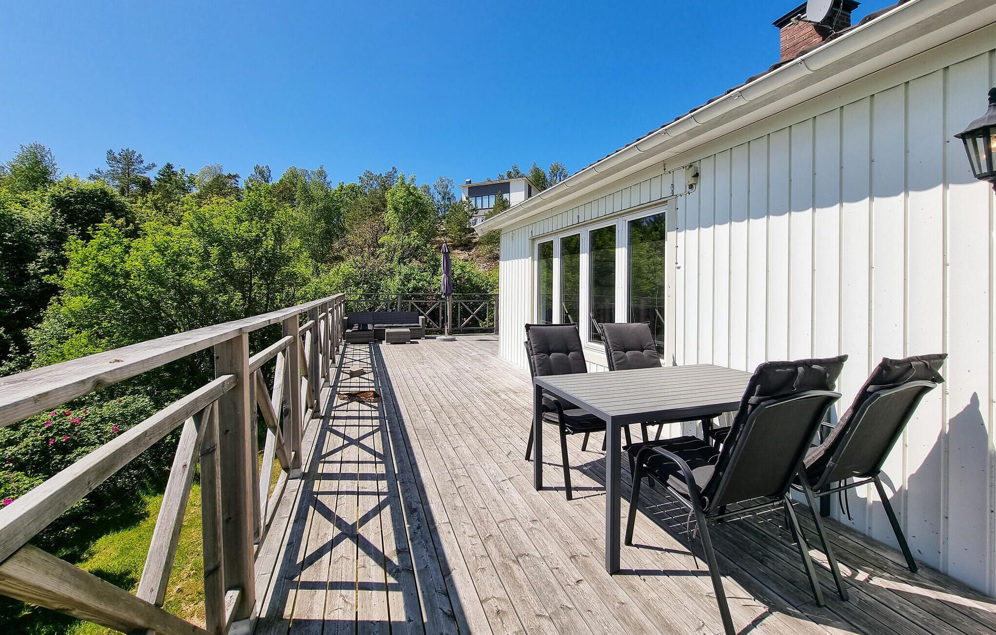 A wooden deck with a table and chairs, overlooking a lush green landscape.