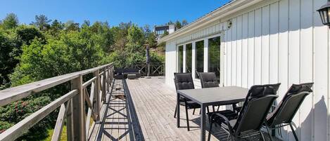 A wooden deck with a table and chairs, overlooking a lush green landscape.