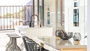 A modern kitchen with a central island, bar stools, and a view of the street.