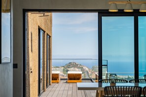 Un balcón con mobiliario de madera y vistas a un pueblo costero.
