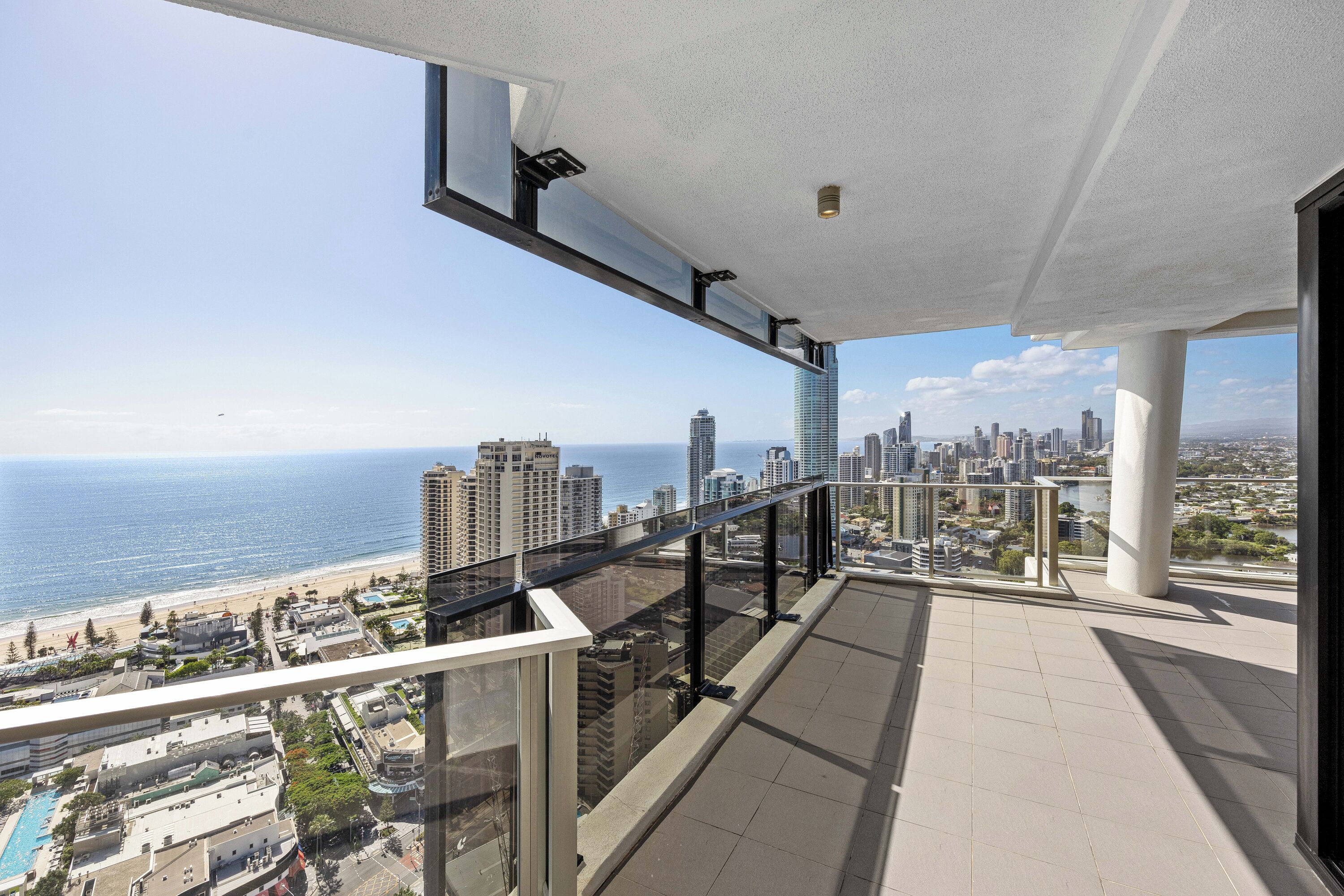 Een balkon van een hoog gebouw met uitzicht op de skyline en het strand.